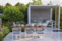 Outdoor dining area  with metal pergola and seating under.  Lower Barn Farm: The Bounce Back Garden, RHS Hampton Court Palace Garden Festival 2021