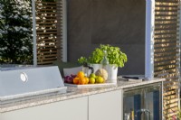 Outdoor kitchen with tray of fruit and basil.  Lower Barn Farm: The Bounce Back Garden, RHS Hampton Court Palace Garden Festival 2021
