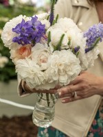 Dame Deborah James Rose held in a bouquet with water from recycling a plastic bottle together with delphinium and salvia