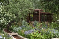 A pavilion crafted from metal screens is set into a formal layout incorporating a rill, rectangular herbaceous beds and trees such as  hawthorn and Salix matsudana tortuosa, dragon's claw willow.
