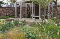 A pavilion crafted from woven willow screens overlooks a sunken pool edged in herbaceous beds planted with a tapestry of lupins, alliums, geums, astrantias, pimpinella, verbascums and ornamental grasses. 