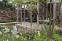 A pavilion crafted from woven willow screens overlooks a sunken pool edged in herbaceous beds planted with a tapestry of lupins, alliums, geums, astrantias, pimpinella, peonies, verbascums and ornamental grasses.