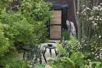 A shady seating areas is enclosed in ferns, hostas, maples and Cornus kousa.