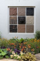 A wall panel features clay tiles, the colours reflected in the border below with purple Heuchera 'Chocolate Ruffles' and Alstroemeria 'Inca Safari'.