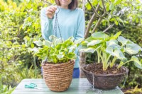 Woman holding up chain on hanging basket