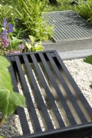 Black bench and small pond covered with metal grid.