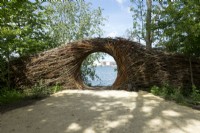 Gateway made of willow branches near the beach with view on the lake made by nature artist Will Beckers.