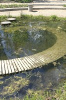 Pond in which the pavement disappears as a spiral into the water filled with plants.