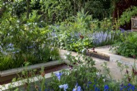 Yorkstone paved path divides colourful borders, step with handmade clay risers and water rill with laser cut insert - Morris  and  Co, RHS Chelsea Flower Show 2022 - Gold Medal