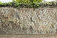 Unusual style of bricklaying in old garden wall with reclaimed bricks laid at an angle. Oblique vertical courses.