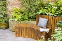 Wooden modern cubic bench and  stone troughs filled with damp-loving dogwoods, hostas, ferns and brunneras  - The Enchanted Rain Garden