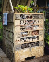 A DIY compost bin made from scrap wood and recycled pallets with built in wildlife spaces and homes for insects and small mammals including a hibernating hedgehog.