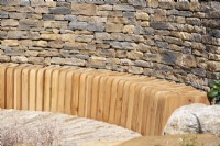 Curved slatted bench next to a dry stone wall - The RAF Benevolent Fund Garden, RHS Chelsea Flower Show 2022 - Silver Medal
