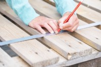 Woman marking a line across all of the planks on the pallet