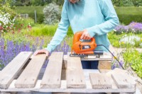 Woman sawing the planks to the correct lengths