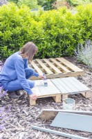 Woman painting the pallets and wooden planks