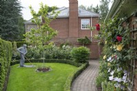 Wire sculpture of a man gardening by Derek Kinzettin the front garden at Hamilton House garden in May 