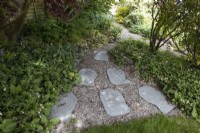 Rustic paving slabs and gravel lead a path from a wide end to a narrow end in a  triangular formation. Spring