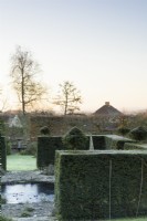 Yew hedges frame a pond in a formal town garden in winter
