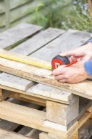 Woman marking the planks of wood at the same lengths as the pallet