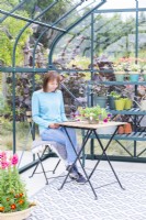 Woman sitting in greenhouse reading magazine