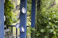 Old teacups are repurposed into decorations on a blue wooden shed. Lewis Cottage, NGS Devon garden. Spring.