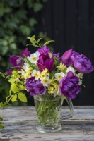 Purple tulips and minature Narcissus arranged with foliage in glass vase