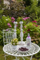 Table decoration with bottle lamp in front of a hydrangea bed