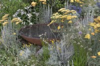 Achillea and mixed perennials surround a corten steel water feature in the RHS Planet-Friendly Garden at RHS Hampton Court Palace Garden Festival 2022