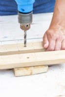 Woman drilling holes for the bolts in the pieces of wood