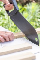 Woman sawing the wood to the correct lengths