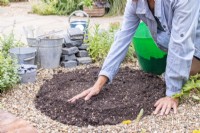 Woman spreading compost evenly around the marked area