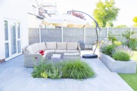 Large sofa in a seating area separated from the rest of the garden by a raised bed