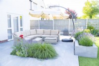 Large sofa in a seating area separated from the rest of the garden by a raised bed
