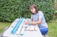 Woman painting all of the pieces of wood blue