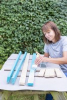 Woman painting all of the pieces of wood blue