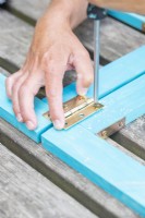 Woman attaching both wooden frames with the hinges