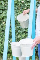 Woman hanging buckets on the hooks on alternate sides