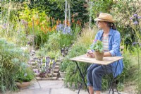 Woman sitting at table near sloped crevice garden