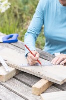 Woman marking where to cut the planks to create the sides