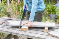 Woman sawing the wooden planks to the correct lengths