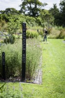 Black wooden posts with the names of renowned women gardeners used to identify growing areas at a flower farm in July