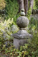 Stone finial topped with pebbles in a country garden in November