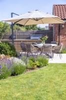 Shaded seating area next to outdoor kitchen and mixed border