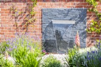 Waterfall feature on layered slate backing surrounded by plants