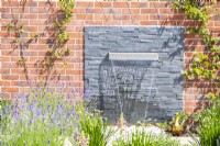 Waterfall feature on layered slate backing surrounded by plants