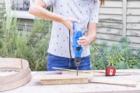 Woman drilling three holes in the longest piece of wood