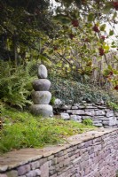 A tower of three Ming dynasty column bases topped with a river pebble in a country garden in November