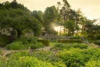 A view over plantings on the main terrace at sunrise at Parcevall Hall Gardens in June