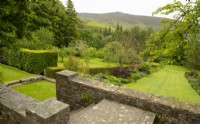 A view over the red borders to Simon's Seat from a terrace at Parcevall Hall Gardens in June.